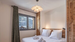 Quarto com cama, janela com vista, cabeceira de madeira e luminária no teto.