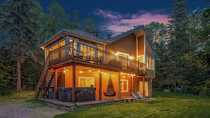 Eine zweistöckige Holzhütte mit Balkon, Sitzgelegenheit im Freien und Whirlpool.