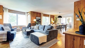 Ein modernes Wohnzimmer mit einer Couch, Sesseln, einem Couchtisch und einem Essbereich mit Stühlen und einem Tisch.
