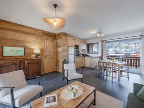 Ein modernes Wohnzimmer mit einer Holzwand, einem Essbereich mit Aussicht und einer Küche mit Holzausstattung.