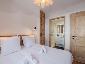 Ein Hotelzimmer mit Bett, einer Holztür, einem Badezimmer mit Spiegel und einem Handtuch auf dem Bett.