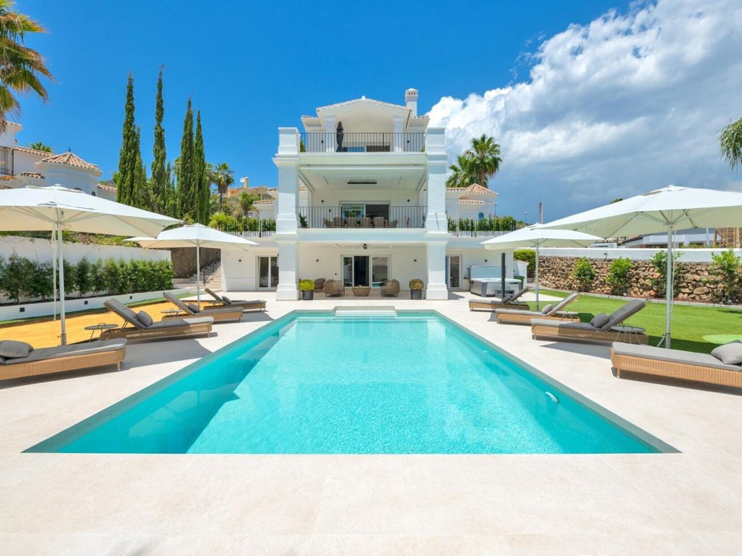 Una casa de dos pisos con piscina, mobiliario exterior y vistas del paisaje circundante.