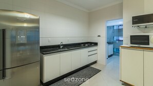 A modern kitchen with stainless steel appliances, white cabinetry, and a black countertop.