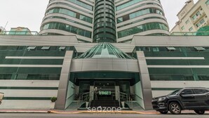 A modern building with a curved facade, large windows, and a prominent entrance with a glass canopy.