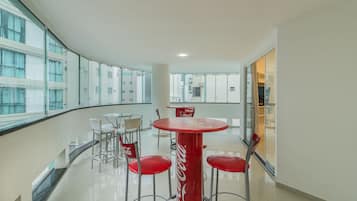 A modern interior with a round table and red chairs, large windows, and a Coca-Cola branded table.