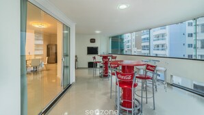 A modern apartment with a balcony, furnished with red Coca-Cola branded chairs and tables, and a city view.