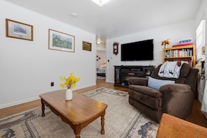 A living room with a wooden coffee table, a brown armchair, a television, and a bookshelf.