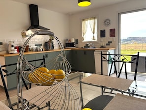 A modern kitchen with a hanging lemon basket, a dining area with a glass table, and a view of the countryside. - Cottage, pets, parking - 6 guests (Cusset)