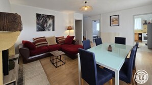Ein modernes Wohnzimmer mit einem Glastisch, roten Sofas und einem Couchtisch aus Holz.