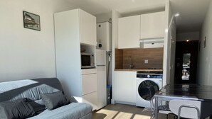 Un espai vital compacte amb un sofà, una rentadora, un microones i una petita zona de menjador.