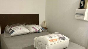Un llit amb un llençol gris i dos coixins, un dels quals té una etiqueta que diu "Anti-acariens".