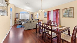 A dining area with a wooden table and chairs, a chandelier, and a dining table set with plates and glasses. - The River City Retreat (Jacksonville)