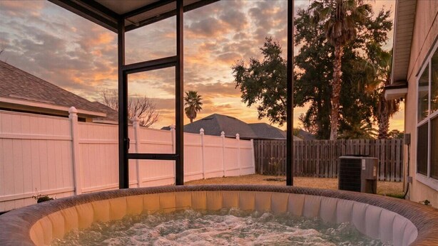 A hot tub with a view of a sunset and a wooden fence in the background. - The River City Retreat (Jacksonville)