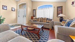 A living room with a sofa set, a coffee table, and a door leading to another room. - The River City Retreat (Jacksonville)