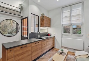 Eine moderne Küche mit schwarzem Arbeitsplatz, Holzschränken, einer Spüle und einem Fenster mit Jalousien.