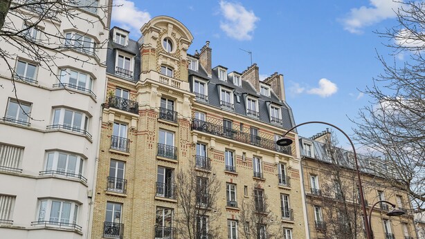 Un edificio de varios pisos con balcones, ventanas amplias y un estilo arquitectónico clásico.