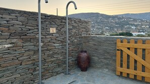 A stone wall with metal fixtures and a wooden gate. - Ammos Andros Accommodation (Ormos Korthiou)