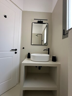 A modern bathroom with a white sink, black fixtures, and a mirror above it. - Ammos Andros Accommodation (Ormos Korthiou)