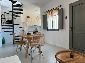 A modern kitchen with white cabinets, a built-in stove, and a dining area with wicker chairs and a wooden table.