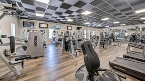 Een sportschool met diverse fitnessapparaten, waaronder loopbanden en krachttoestellen.