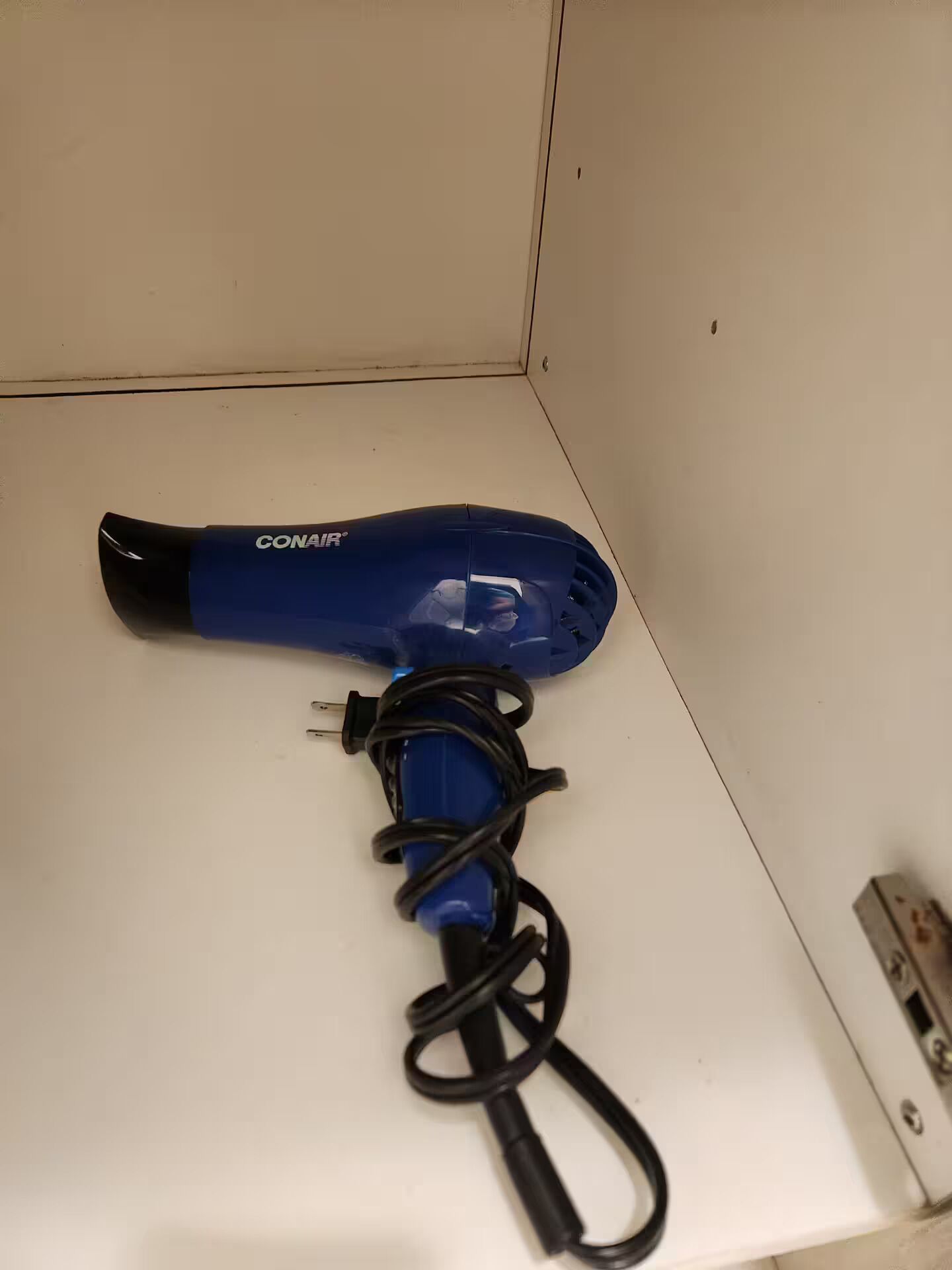 A blue hairdryer with a cord on a white surface.