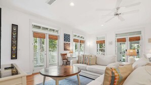 Un salon spacieux avec un canapé blanc, une table basse ronde et un ventilateur de plafond.