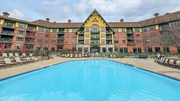 Et hotel med central swimmingpool, flere balkoner og en markant facade i gult og brunt.