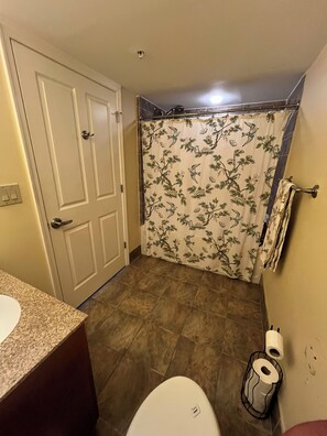 Un baño con inodoro, cortina de ducha estampada con flores y un perchero.