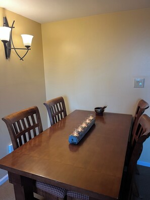 Une table à manger avec quatre chaises, un chandelier et des appliques murales.