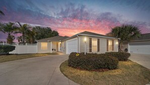 A single-story house with a garage, a covered front porch, and a well-maintained lawn. - Pet-Perfect Village Retreat with Fenced Yard in a Prime Spot – Book & Save (The Villages)