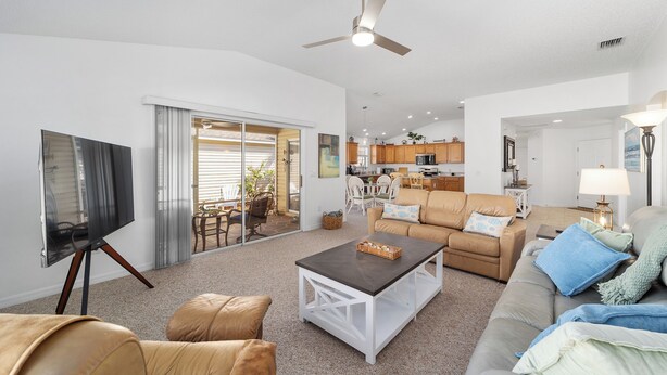 A spacious living room with a flat-screen TV, a ceiling fan, and a large window. - Pet-Perfect Village Retreat with Fenced Yard in a Prime Spot – Book & Save (The Villages)