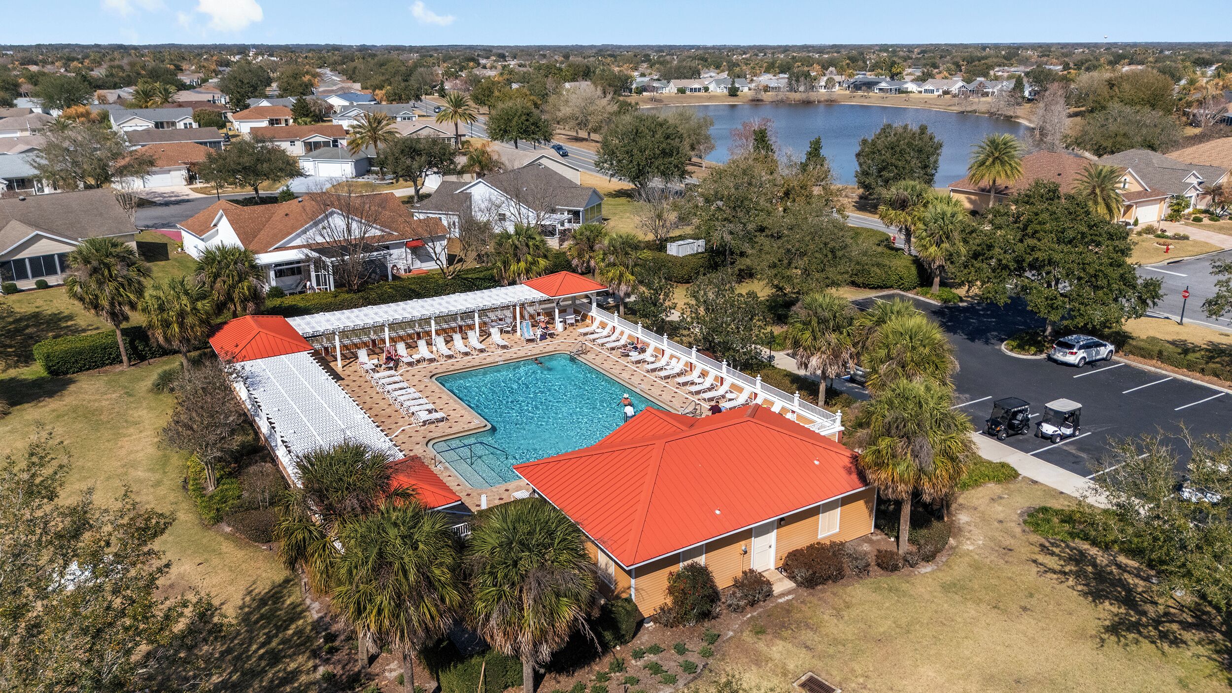 A residential area with a swimming pool, covered patio, and a view of a lake.