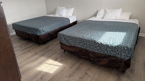Deux lits simples avec une literie à motifs, un plancher en bois et des murs blancs.