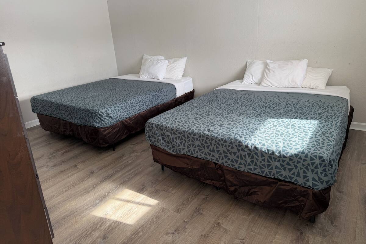 Two single beds with patterned bedding, wooden flooring, and white walls.