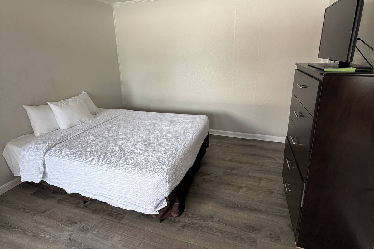 A bedroom with a bed, a dresser, and a television on a dresser.