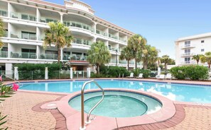 A hotel with a swimming pool, palm trees, and a multi-story building with balconies. - The Inn at Seacrest Beach Unit 207 (Alys Beach)