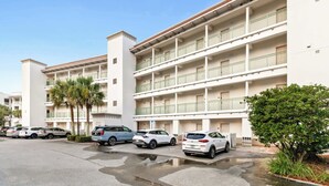A multi-story hotel with a parking lot in front. - The Inn at Seacrest Beach Unit 207 (Alys Beach)