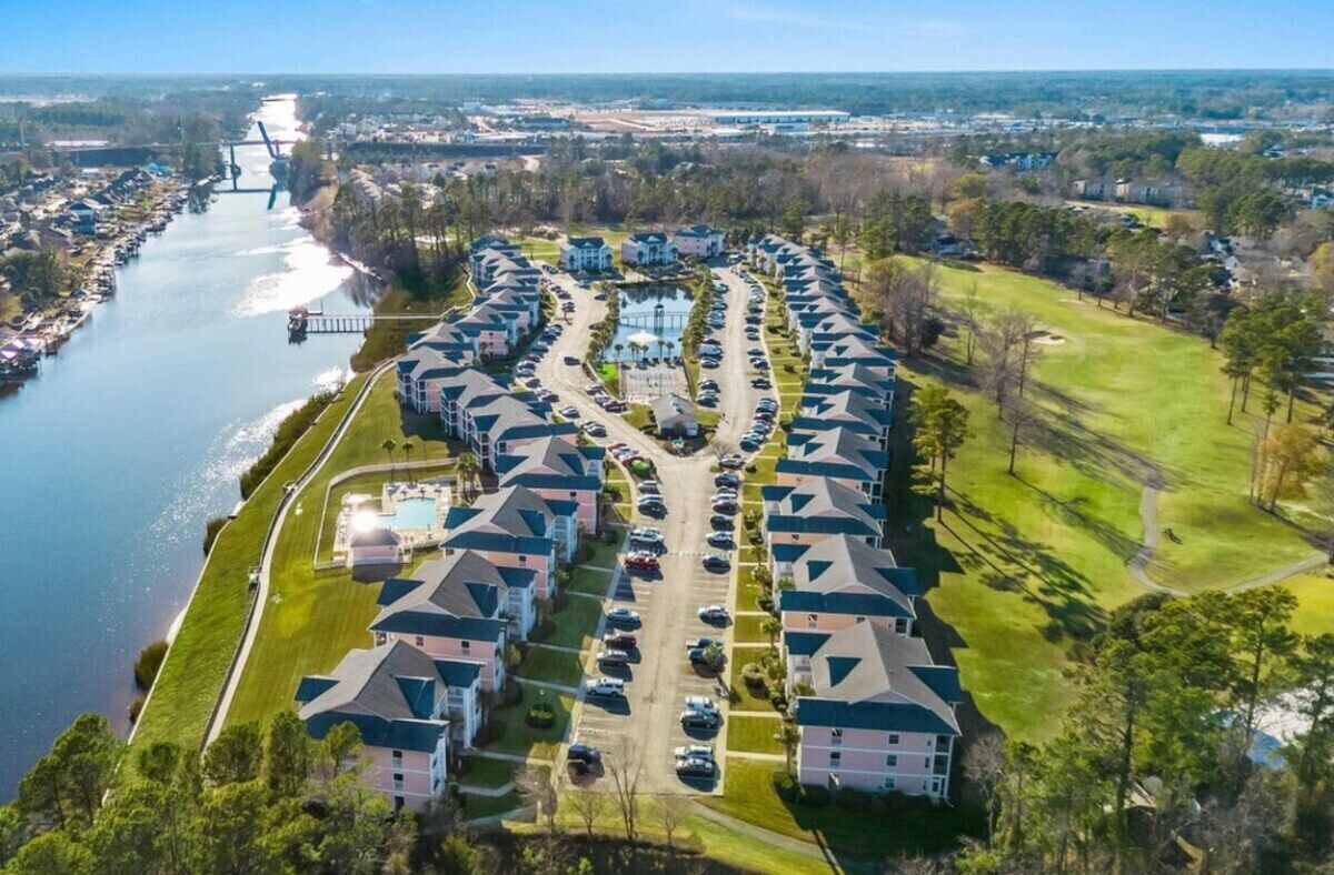 A residential area with houses arranged in a semi-circular pattern around a body of water, with a bridge in the background.