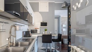 Une cuisine moderne dotée d’appareils électroménagers en acier inoxydable, d’un four à micro-ondes encastré et d’un petit îlot central avec des tabourets de bar.
