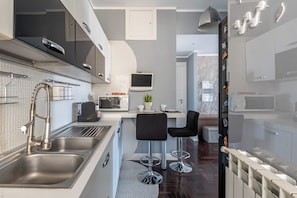 A modern kitchen with stainless steel appliances, a built-in microwave, and a small island with bar stools. - Sunny Suite: the warmth of a finished, modern home for your family. (Palermo)