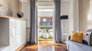 Un salon moderne avec un canapé, une table basse et une vue sur un espace de détente extérieur, accessible par une porte vitrée.
