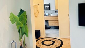 Een moderne keuken met een ingebouwde oven, een spoelbak en een aanrecht. Op de vloer staat een grote potplant en een kleine speaker.