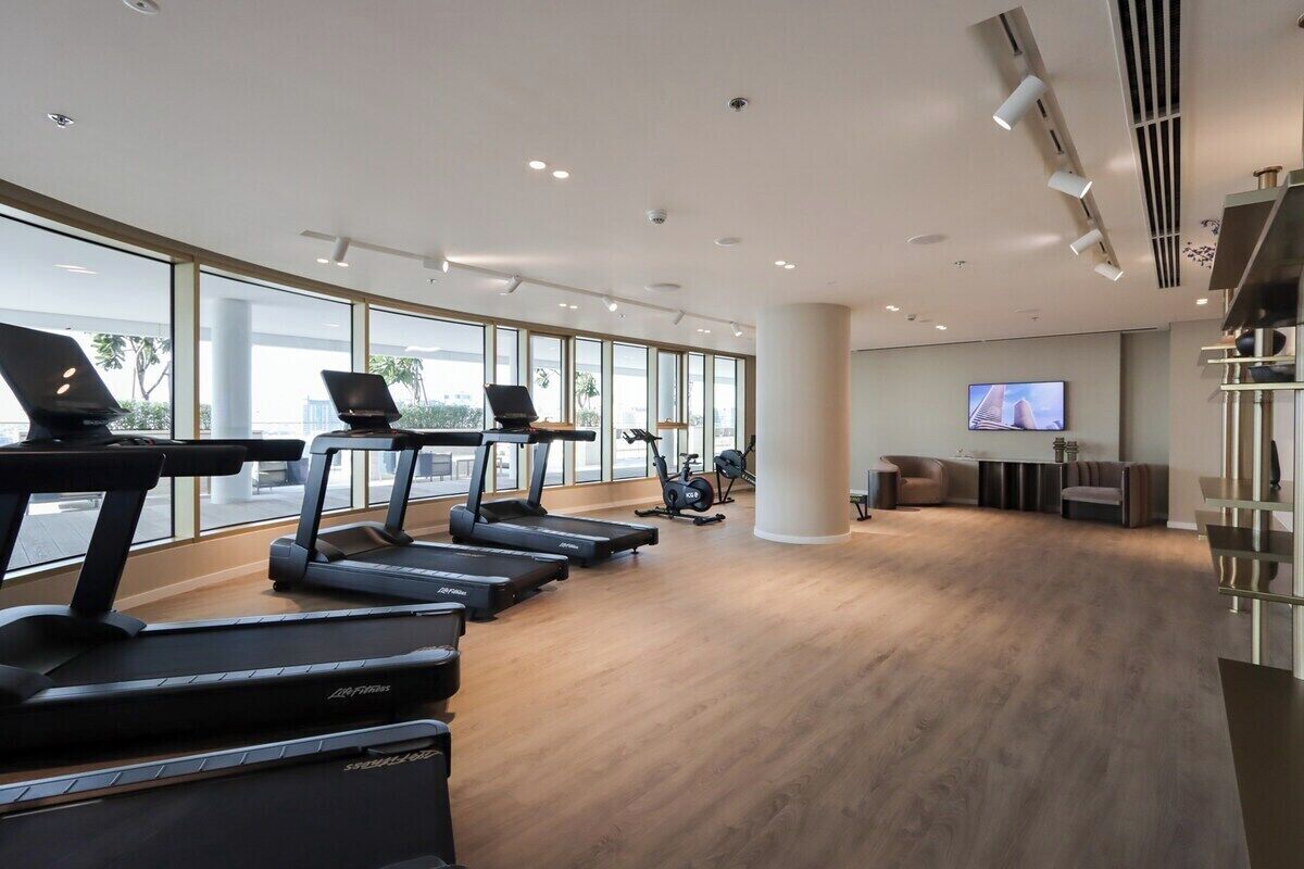 A modern gym with treadmills, stationary bikes, and a TV screen.