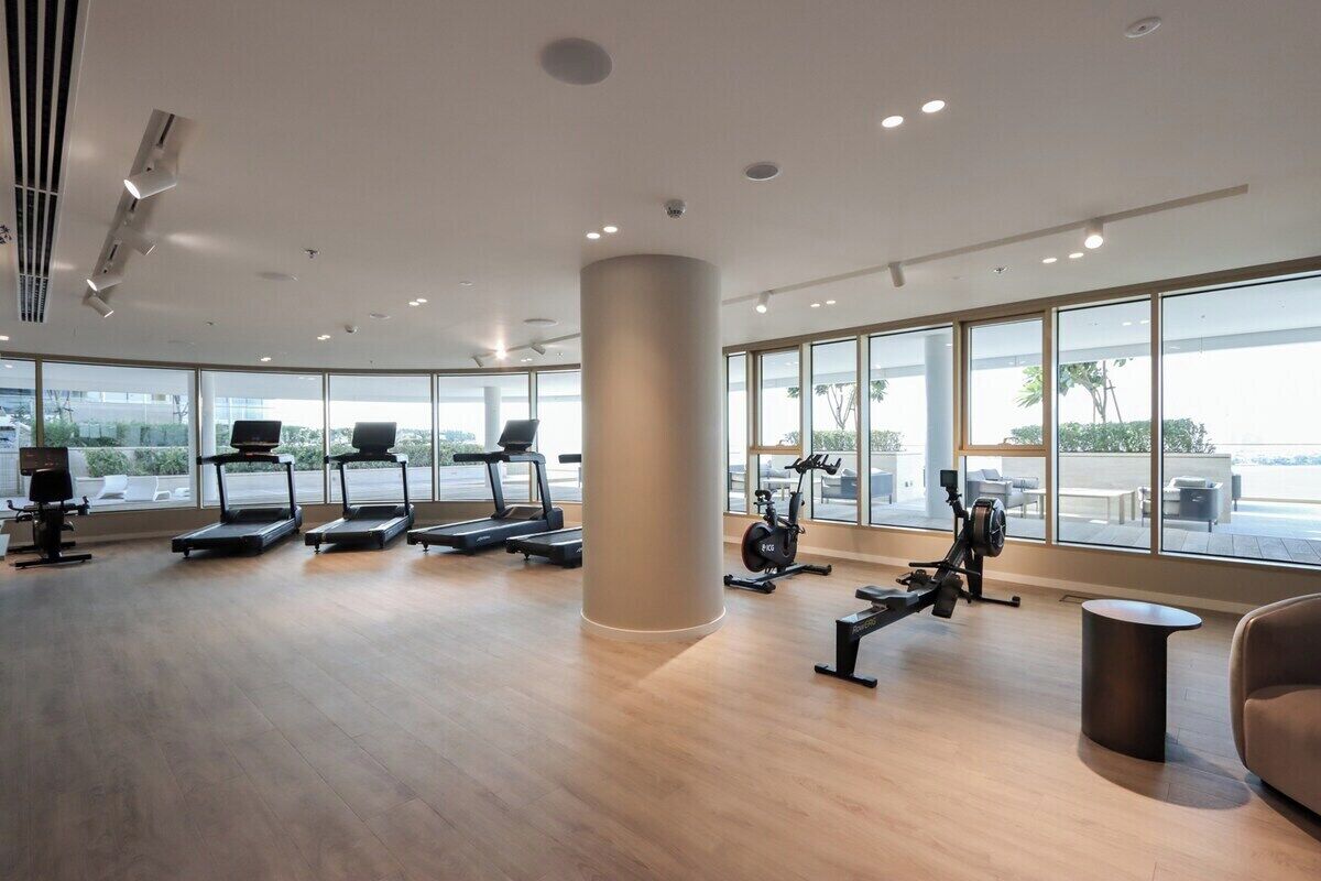 Ein geräumiges Fitnessstudio mit Laufbändern, Crosstrainern und Rudergeräten.