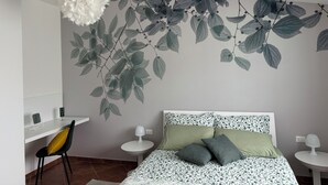 A bedroom with a bed, two bedside tables, a chair, a desk, and a wall-mounted light fixture. - House surrounded by olive grove 900mt from the sea (Orosei)