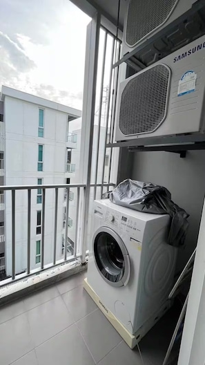 A laundry room with a Samsung washing machine, a dryer, and a Samsung air conditioner unit. - The Base Downtown Phuket By Ploy (Wichit)