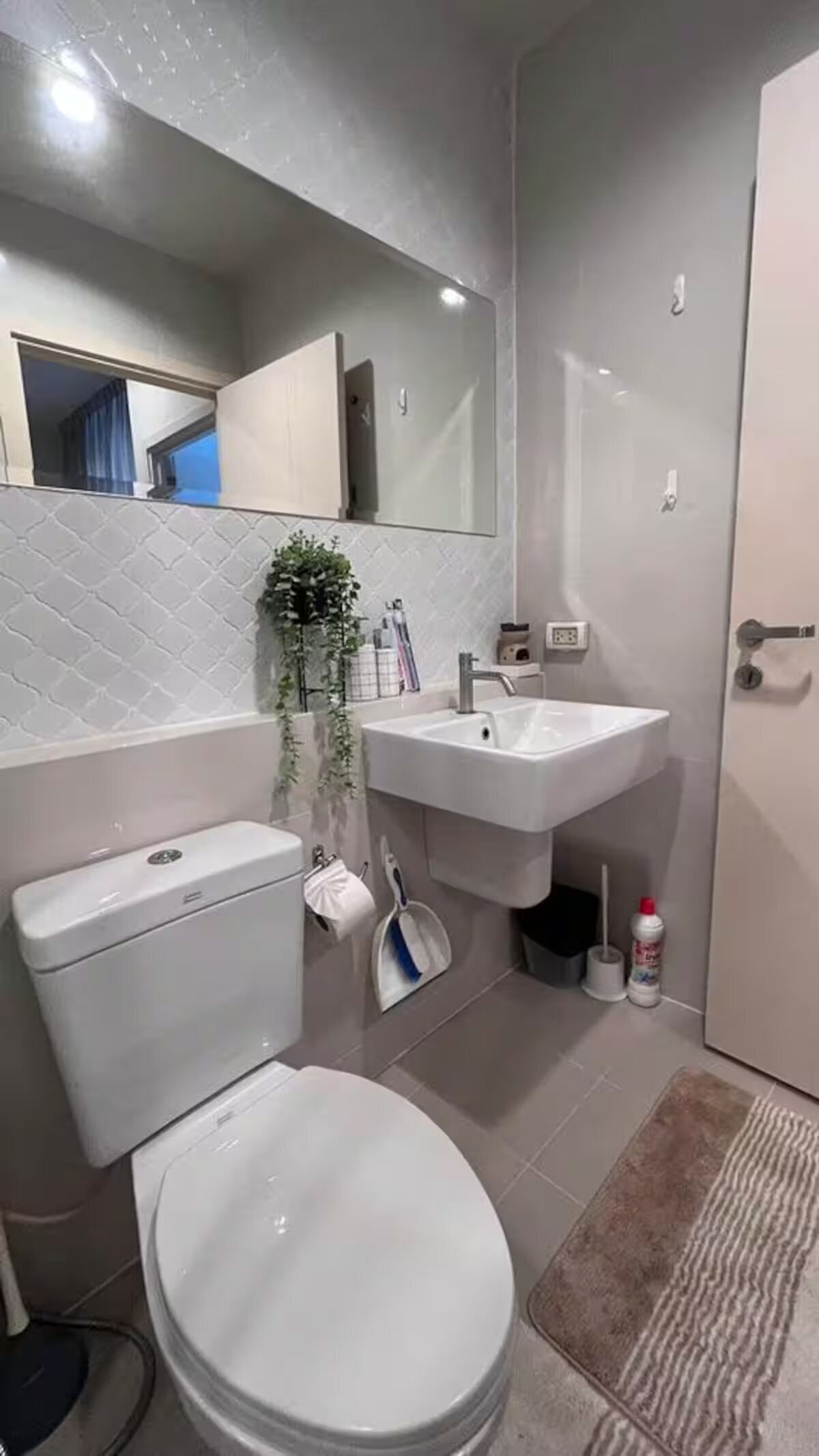 Een moderne badkamer met toilet, wastafel en spiegel.