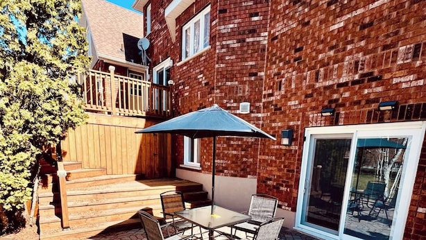 A patio with a table and chairs, a wooden deck, and a brick building with a glass door.
