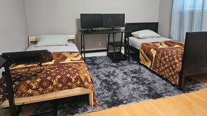 A small, neatly arranged bedroom with two beds, a desk, and a TV. - Home sweet Home (Surrey)