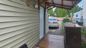 A covered porch with a wooden beam structure, a garage door, and a vehicle parked outside. - Home sweet Home (Surrey)